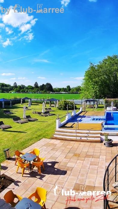 Garten des Club KARREE mit Liegen, Salzwasserpool und Terrasse unter blauem Himmel.
