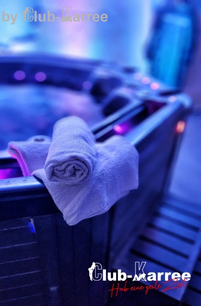 Whirlpool mit einem gerollten Handtuch am Rand, lila beleuchtet.